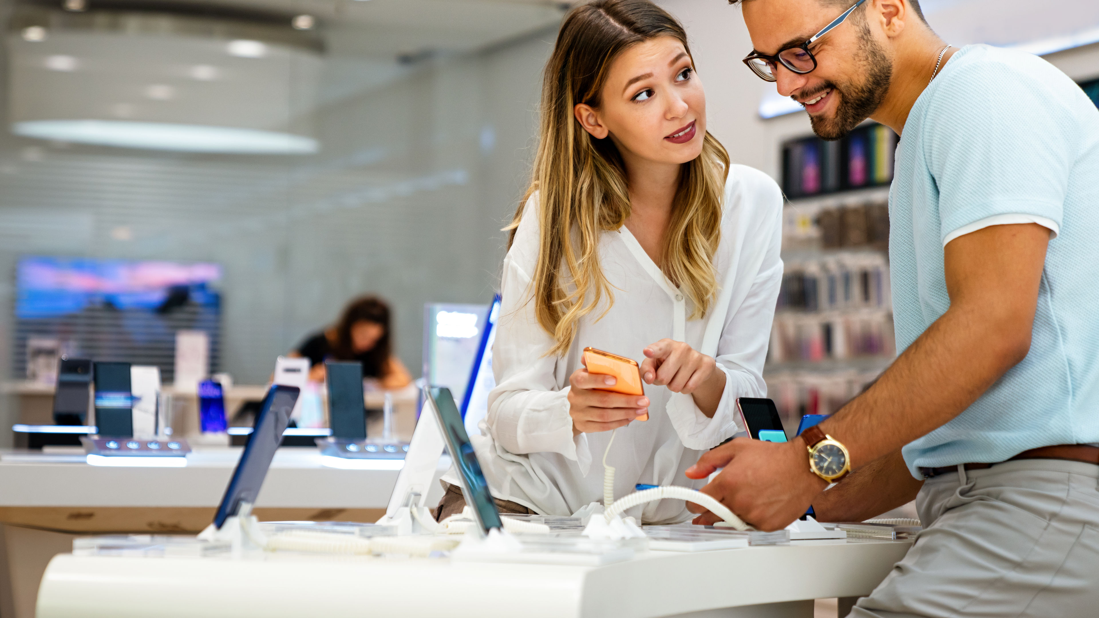 In a trendy mobile shop, a couple of young people are browsing through the latest smartphones.