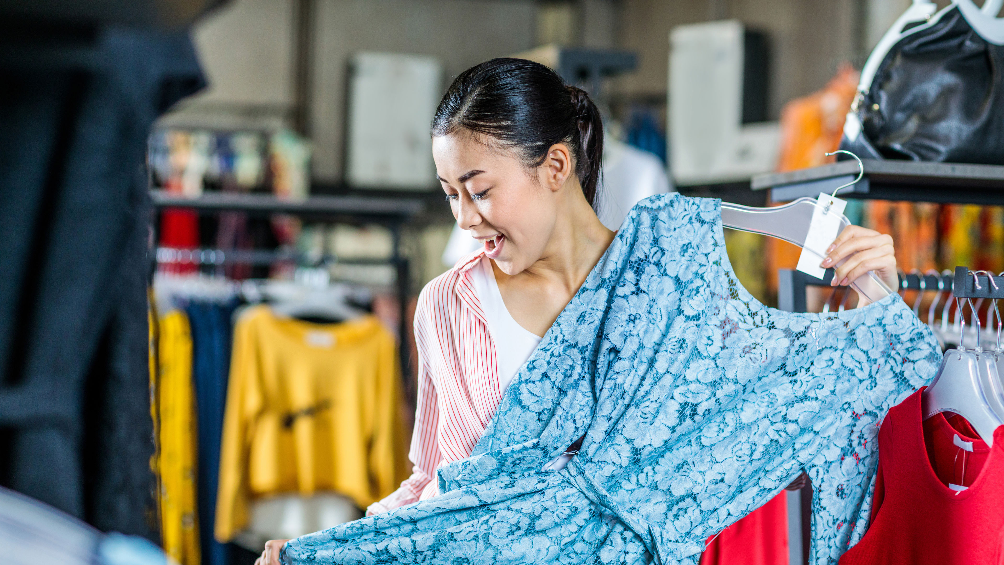 Asian hipster girl choosing clothes in shopping mall.