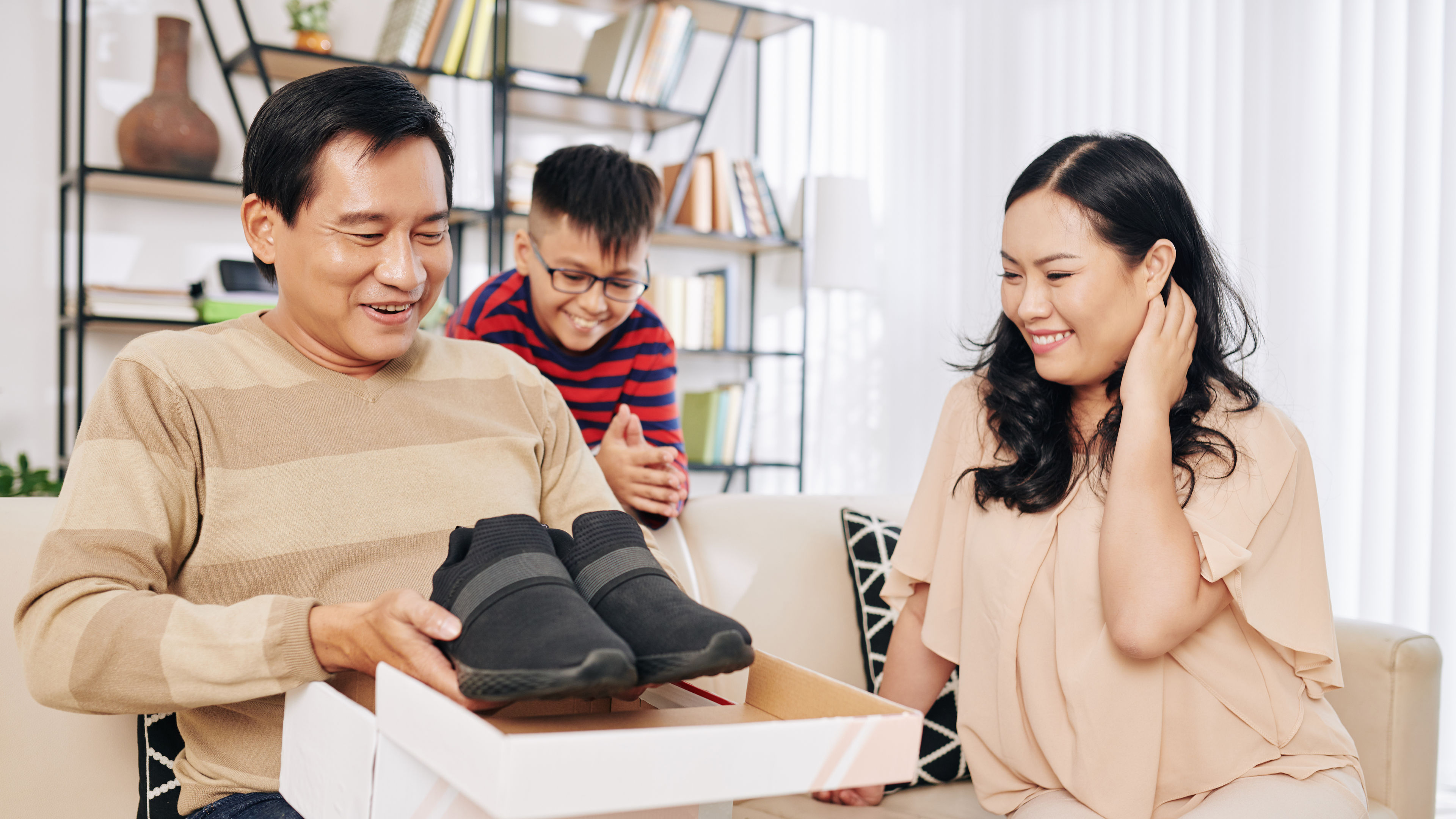 A man smiling and holding black shoe