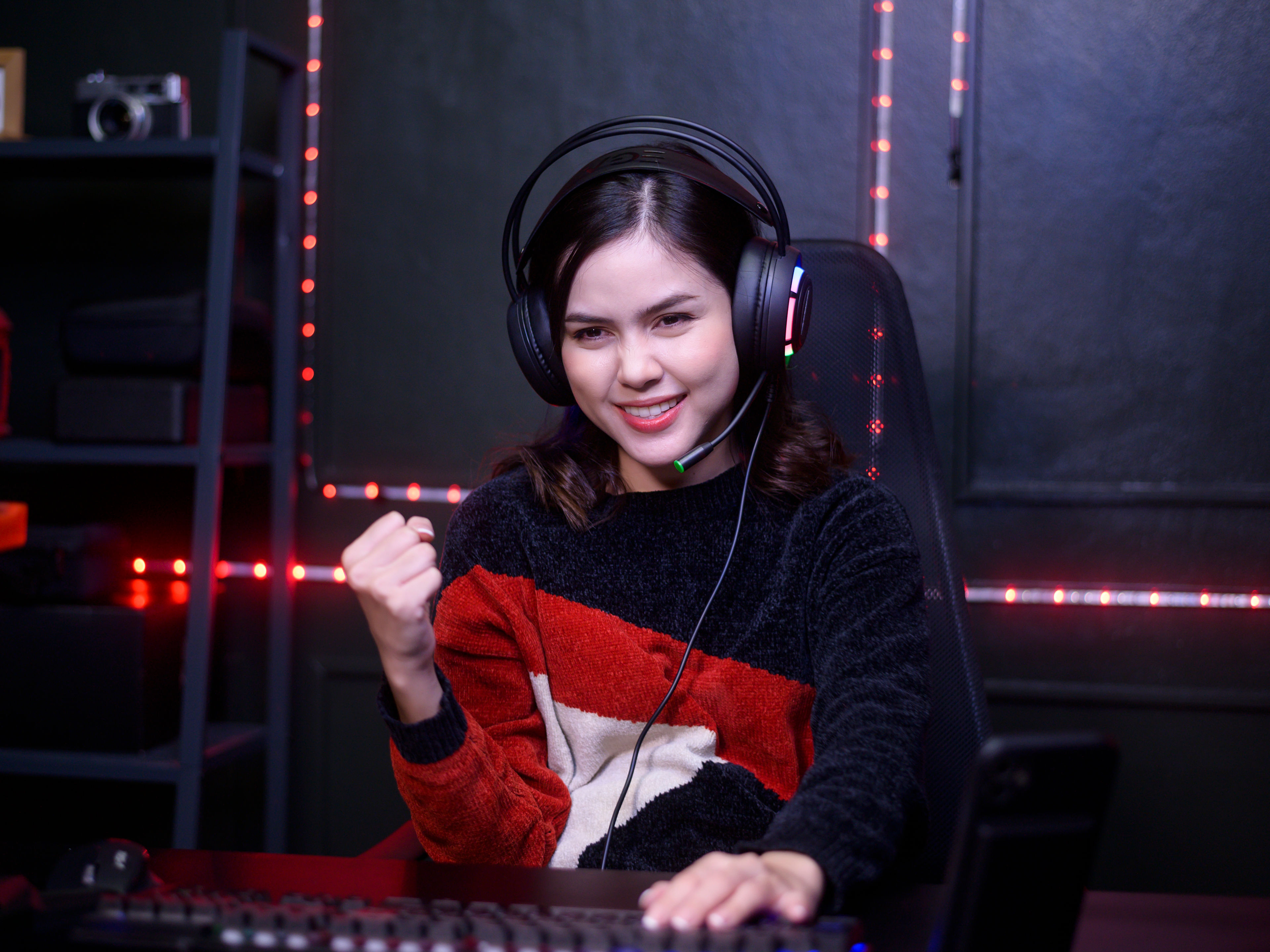 A young woman wearing a headset is sitting at a gaming desk
