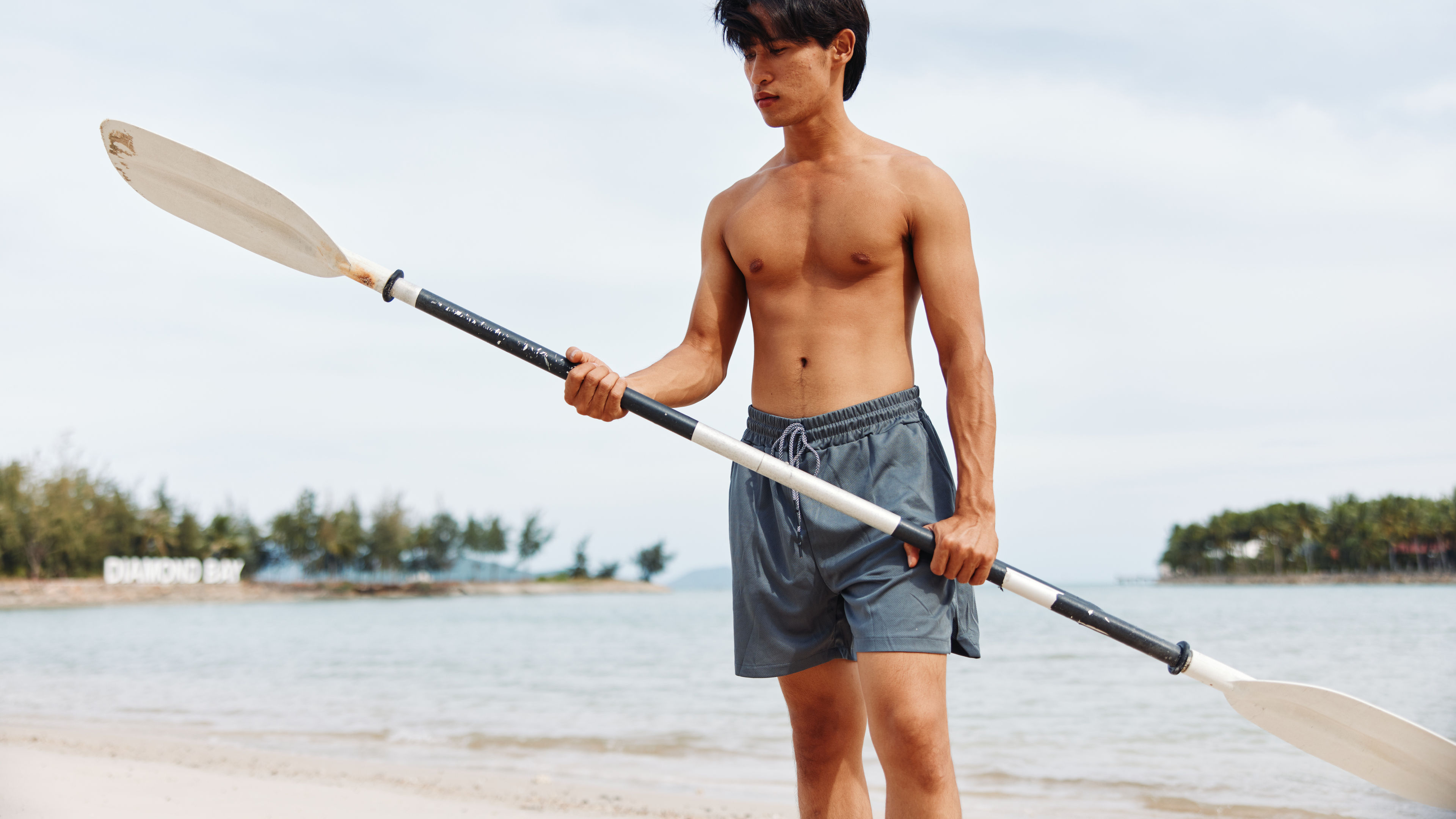Asian man holding paddleboarding on the Beach
