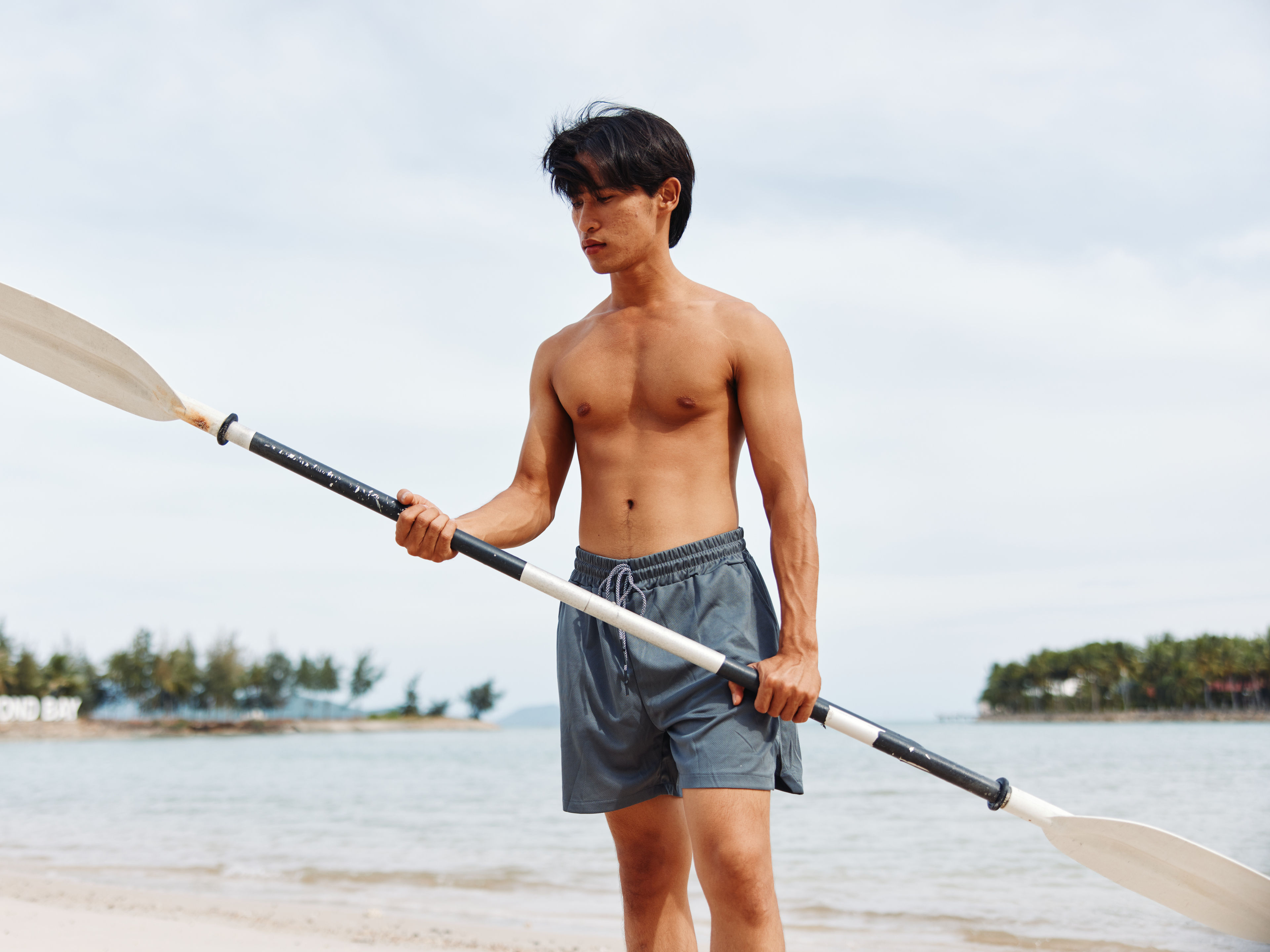 Asian man holding paddleboarding on the Beach