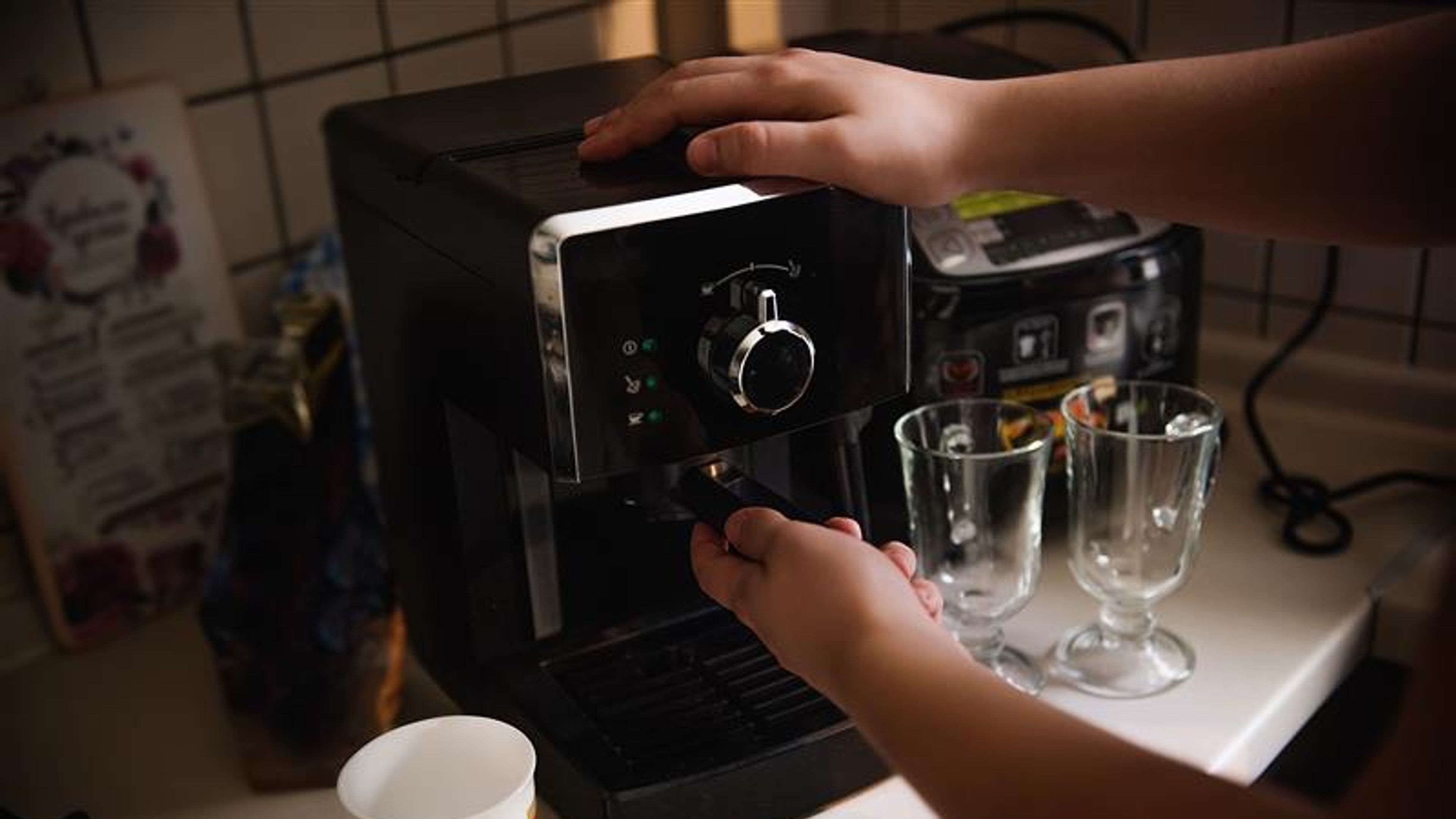 The hands of a young man make coffee from a coffee machine. Morning latte for breakfast at home