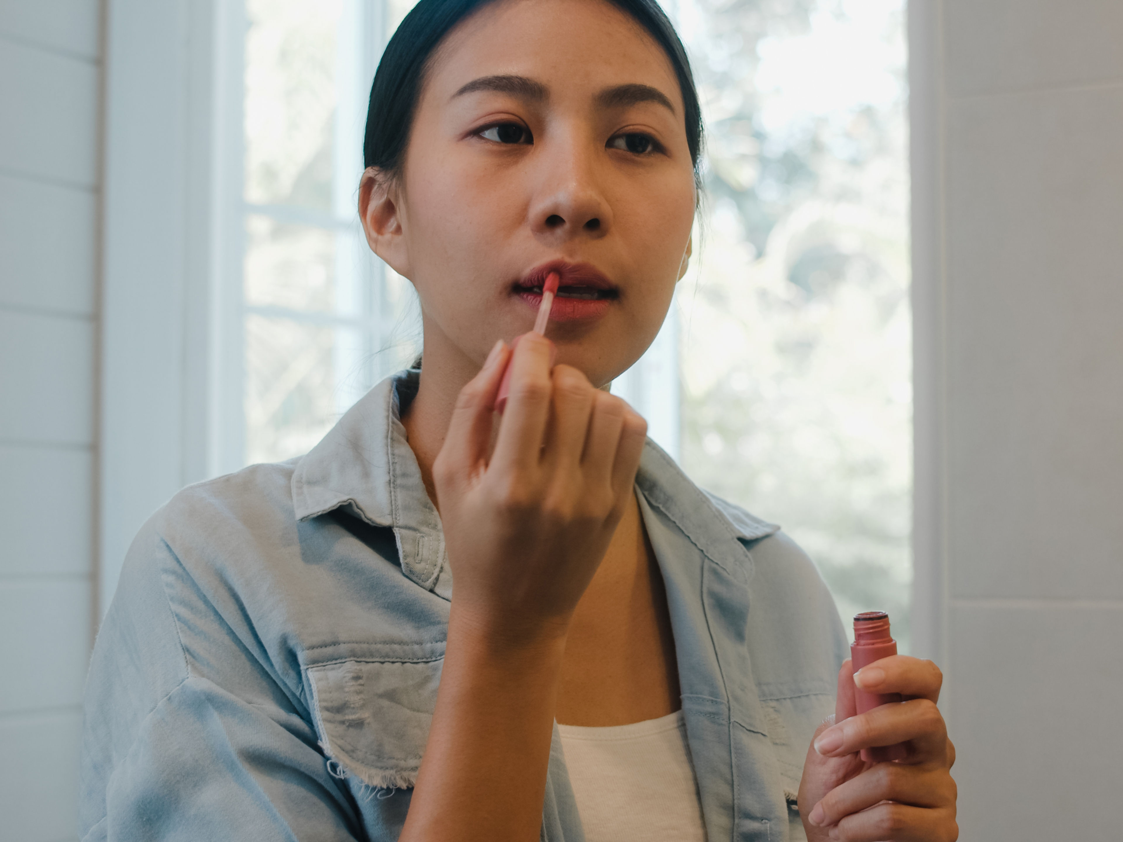 Woman applying lip gloss. 