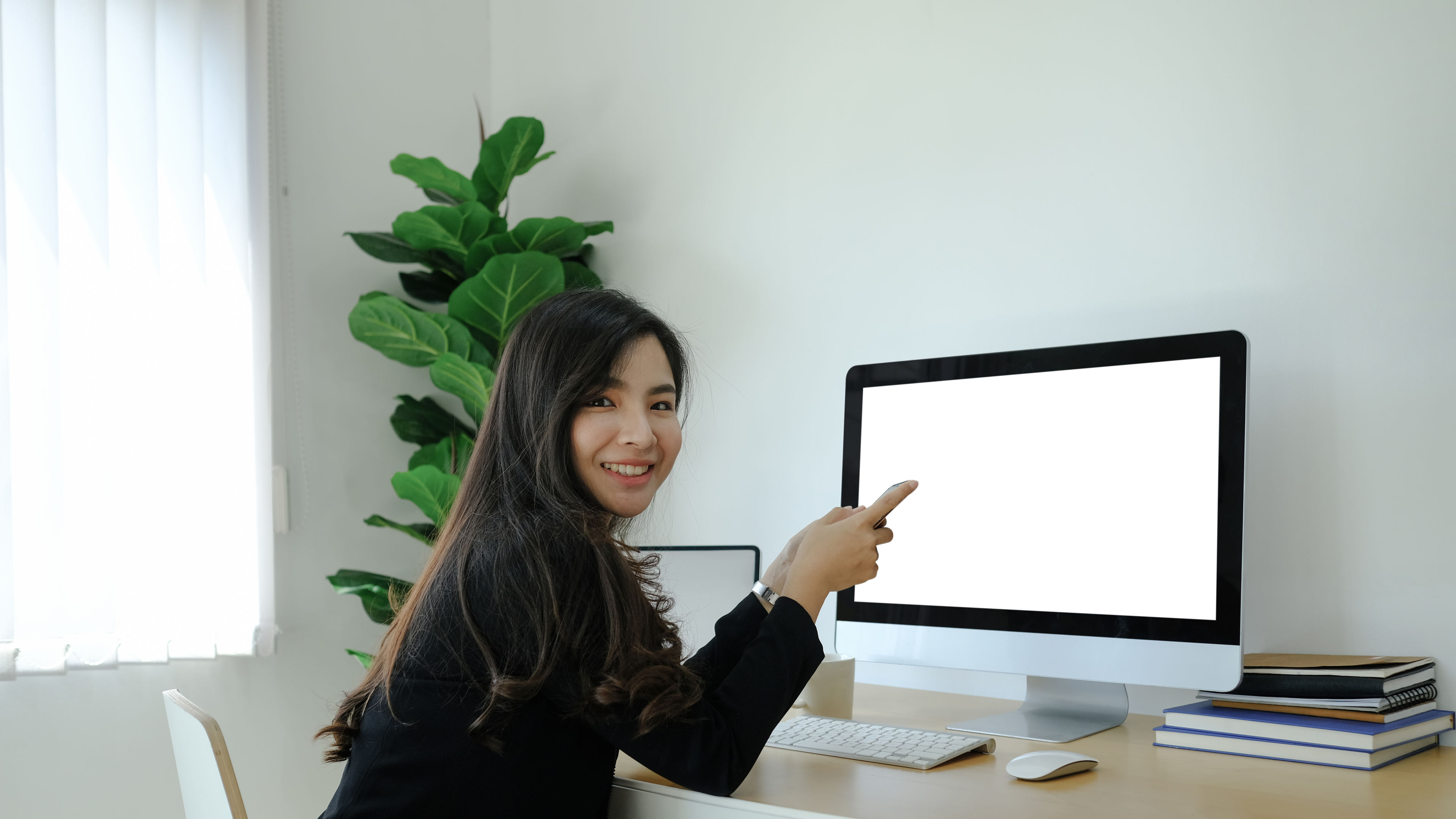 Woman sitting in front of monitor and smiling.